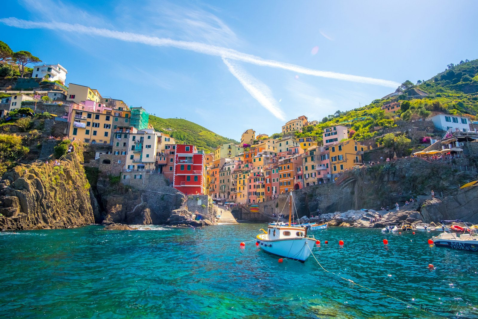 Blå fiskerbåd trukket op foran farverige huse på klippen i en af byerne i Cinque Terre