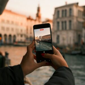 Turist filmer kanalbygninger i Italien med sin smartphone ved solnedgang